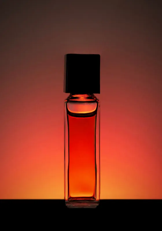 زجاجة عرار نجد، عطر الدار، يتوهّج سائلها بلون الكهرمان أمام ضوء دافئ
